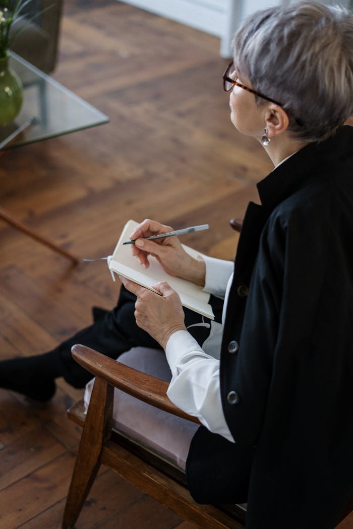 services-04 A professional woman with glasses taking notes while seated indoors, depicting consultation or therapy.